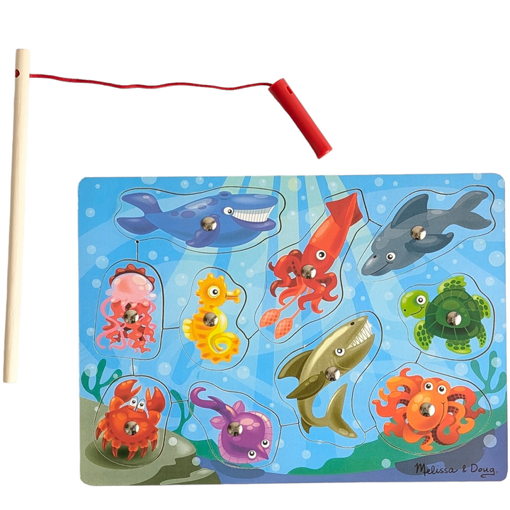 Melissa & Doug, Wooden Fishing Magnetic Puzzle Game, Cognitive & Motor Skills Development , Featuring artwork of aquatic animals, this magnetic wooden puzzle game is the perfect catch-and-release fishing program. Enjoy the task of returning the ten vibrant sea friends to the depths after using the magnetic fishing rod to "catch" them from the game board! An inventive approach to promote fine motor abilities and hand-eye coordination.