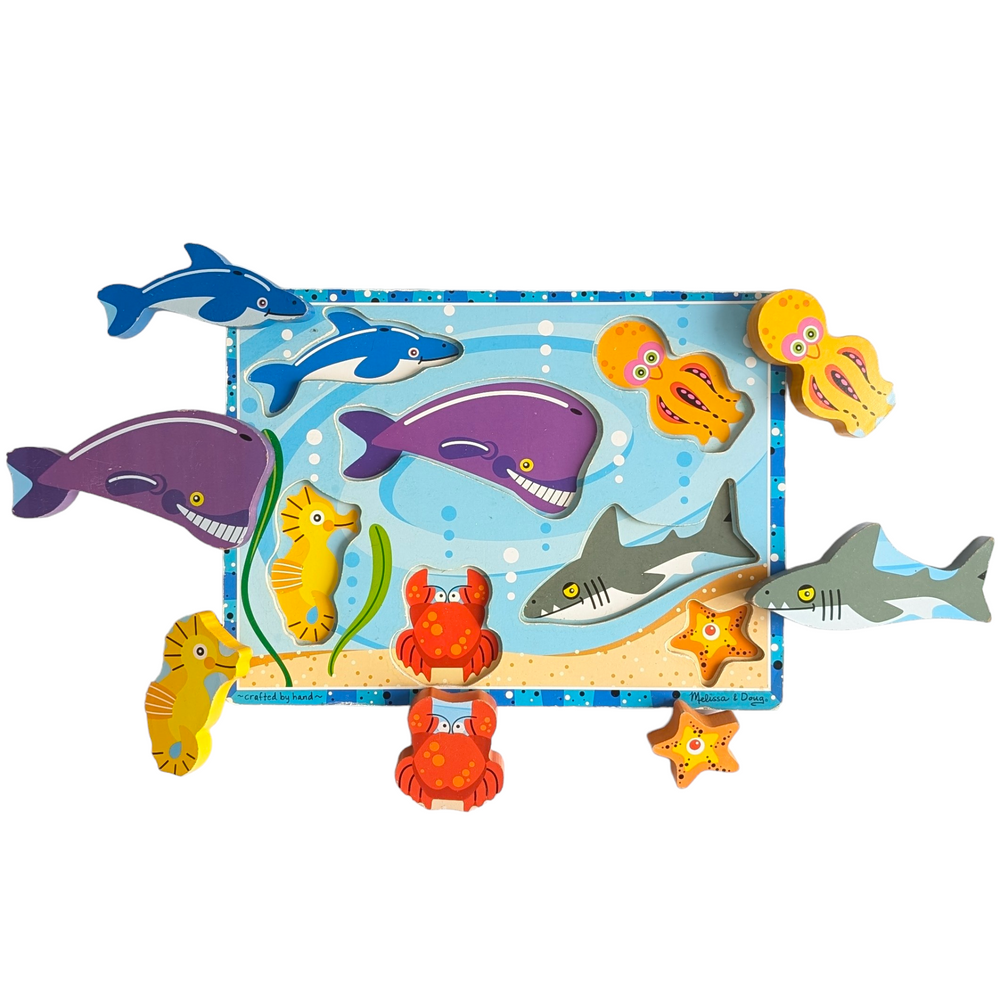 Melissa & Doug, Sea Creatures Chunky Puzzle, Cognitive & Motor Skills Development, Melissa and Doug's chunky sea creature puzzle. Big wooden pieces indicate creative play. Puzzle board with seven pieces and picture underneath the pieces. This extra-thick wooden puzzle features seven easily graspable aquatic creatures, including an octopus, shark, and whale. For pretend play, the hefty pieces with corresponding full-color pictures underneath can be lifted out of the depths.